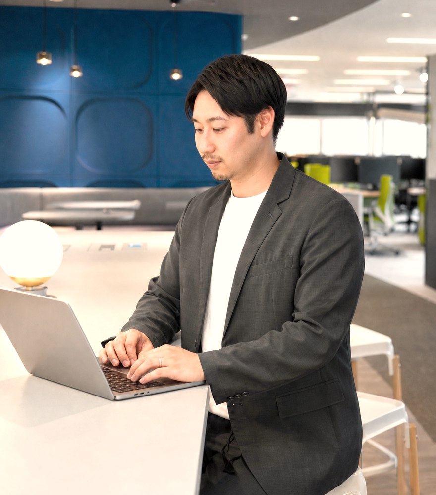 スタンディングテーブルでノートPCに向かう商品管理担当
