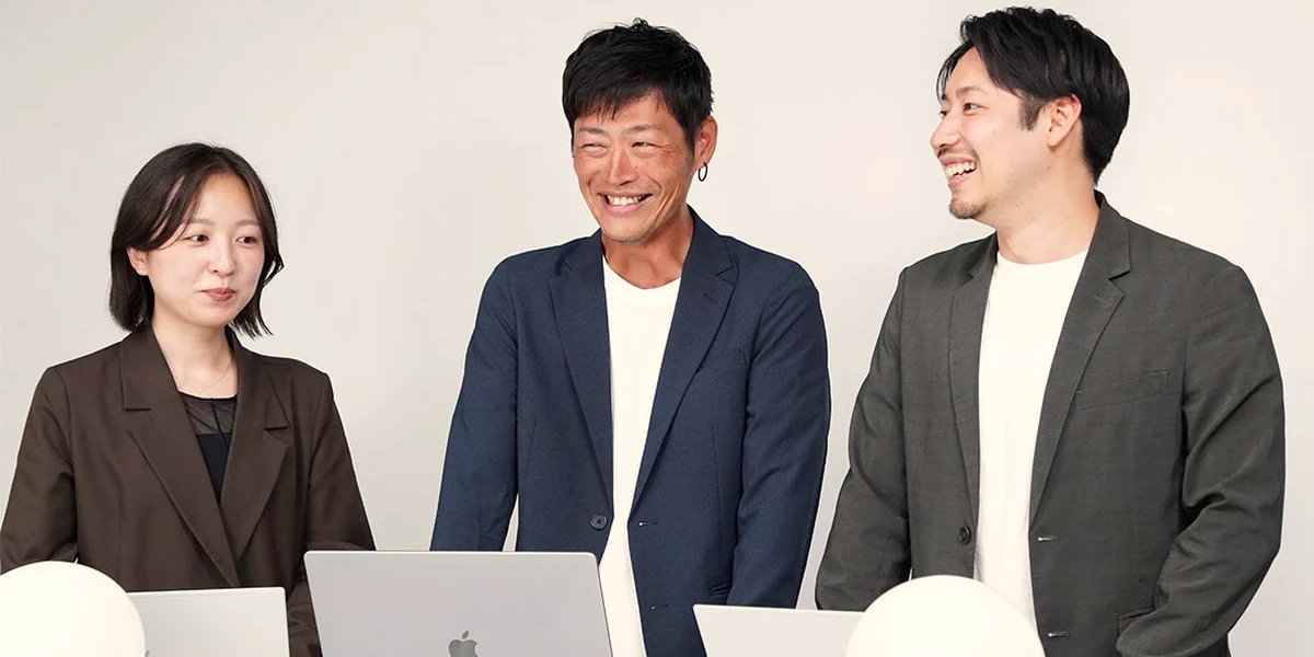 ノートPCを前に3人が笑顔で話している様子